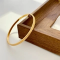 Macro shot of 18K gold plated titanium steel bangle with ribbed texture on walnut tray - Fine Gear Gold (Inner Diameter 5.8cm)