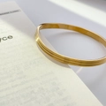 Macro shot of 18K gold plated titanium steel bangle with three parallel fine groove textures - Curved Striped Gold (Inner Diameter 5.8cm)