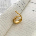 Primer plano de un anillo de serpiente dorado con escamas sobre un libro - US 6 / Estilo de Serpiente de Doble Capa / Dorado