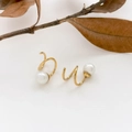 Detail van gouden pareloorbellen met een minimalistisch dubbel helixontwerp op wit - Vaste Parel Stijl