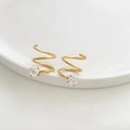 Gedetailleerde close-up van gouden spiraal oorbellen met zirkonia op een witte schaal - Zirconia Stijl