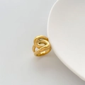 Detalle de anillo dorado con diseño de nudo sobre un plato de cerámica blanca - US 6 / Estilo de Nudo Grueso