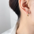 Close-up of model wearing small gold hoop earrings with multi-colored rainbow cubic zirconia - Rainbow Zirconia (1.6cm)