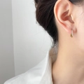 Close-up of golden small hoop earring with clear zircon inlay worn on a model ear - White Zirconia (1.6cm)