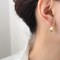 Eleganti orecchini a C geometrici dorati con perla bianca su una modella femminile - Stile Perla Piccola / Oro