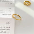 Gros plan d'une bague dorée minimaliste aux lignes artistiques courbes et fluides - US 6 / Ligne Pointue