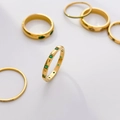 Close-up of gold titanium ring set with green emerald-colored stones and fine crystals - US 6 / Spaced Green Zirconia Band