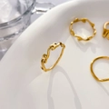 Close-up of minimalist wave gold rings with organic lines on white ceramic tray - Lucky Cloud / US 6