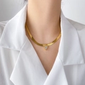 Detail van een gouden slangenketting met een driehoekige zirkoon hanger op een model - Driehoek Zirkonia Slangenketting