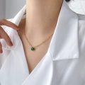 Detailopname van een gouden ketting met een ronde groene edelsteen hanger aan de hals - Ovale Groene Zirkonia Kralenketting