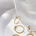 Detailed shot of gold twisted ring with zircon and pearl accents on white silk - Oval Zirconia Twisted Band Ring