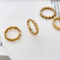 Detaillierte Makroansicht von vier vergoldeten Ketten- und gedrehten Seilringen auf Papier - US 6 / Holle Runde Kette