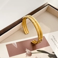 Dettaglio del bracciale rigido dorato a forma di ingranaggio con doppie nervature lucide - Polsino Aperto ad Arco a Doppio Strato (Oro)