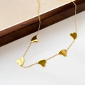 Detail of a gold snake chain necklace featuring five polished heart-shaped pendants - Heart