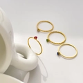 Detailansicht von vier minimalistischen Goldringen mit winzigen bunten Edelsteinen - US 6 / Glatter Schmaler Ring Granatrot