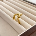 Detailansicht eines goldfarbenen Lava-Rings in einer beigen Schmuckschatulle aus Samt - US 6 / Lava-Flüssigkeit