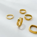 Detailed arrangement of five minimalist 18k gold plated stainless steel rings on white surface - Chunks