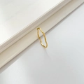 Dettaglio dell'anello dorato ondulato con trama martellata su un libro bianco - US 6 / Onda a Trama Intagliata