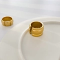 Close-up of golden geometric wide rings with polished mirror finish on white ceramic - US 6 / Large Gourd