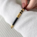 Detail van een minimalistische goud en zwart emaille armband op een witte gebreide mouw - Zwart Emaille Open Stijl