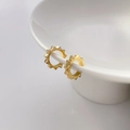 Detailed view of gold gear-shaped hoop earrings on a white ceramic bowl edge - Gear Shape Gold (Diameter 1.3cm)