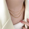 Elegant multi-layer gold snake chain necklace with four textured layers on female model - Multi-Layer Snake Chain