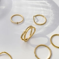 Vista dettagliata anello incrociato con zirconi dorati e fedine minimaliste con ombre d'acqua - US 6 / Doppia Croce