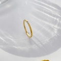 Makroaufnahme eines dünnen Goldrings mit Baguette-Zirkon auf Wellenhintergrund - US 6 / Einzelner Baguette-Zirkonia