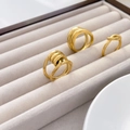 Detailed view of three 18K gold-plated titanium rings with twisted and wide band designs - Twisted Rope