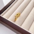 Detailed close-up of a twisted gold knot ring inside a premium jewelry box interior - US 6 / Knot