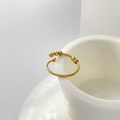 Detailed shot of gold plated wave ring with movable beads hanging on a white ceramic cup - 4-Bead Open