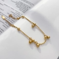 Detailed view of a gold beaded chain bracelet with large polished ball charms on a book - Round Bead Pendant Chain Style