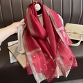 Détail d'une écharpe en soie rouge avec broderie papillon et accents de perles blanches - Bordeaux