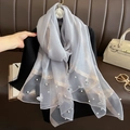 Détail d'une écharpe en soie gris clair avec broderie papillon blanche et perles décoratives - Gris clair
