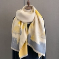 Dettaglio di sciarpa beige caldo con foglie gialle e frange morbide su manichino - Giallo