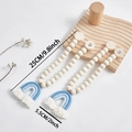 Detail showing 25cm woven rainbow curtain tieback with wooden beads and white tassels - One Size / Light Blue