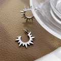 Macro detail of silver sun-shaped stud earrings with sharp radiating lines on leather - Steel Sunflower Earrings
