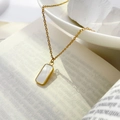 Detalle del collar de oro con colgante rectangular de nácar sobre un libro abierto - Concha rectangular pequeña