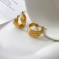 Detail view of 18K gold plated tiered wavy hoop earrings on a minimalist white backdrop - Four Layer Style