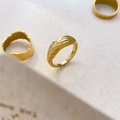 Detail von drei 18K vergoldeten Titanstahlringen mit Krater- und vertikaler Streifenstruktur - US 6 / Hand in Hand