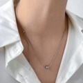 Collier chaîne serpent avec perles argentées porté sur une chemise blanche chic - Grandes et Petites Perles / Acier