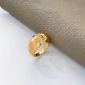 Vista macro dell'ampio anello in acciaio inossidabile placcato oro 18K su pelle grigia - US 6 / Superficie ad Arco Interrotta