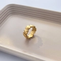 Detail eines 18K vergoldeten Ringes mit Wellenstruktur auf einem beigen Keramiktablett - US 6 / Verbundenes Herz