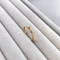 Nahaufnahme eines goldenen Kordelrings mit rundem Zirkonia in einer Samt-Schmuckbox - US 6 / Gedrehter runder Zirkon