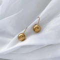 Detailed view of polished golden hollow ball drop earrings on white silk fabric - Hollow Sphere