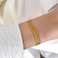 Dettaglio del bracciale a più strati dorato con catene intrecciate indossato al polso - Catena Sottile a Più Fili