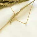 Gros plan du collier minimaliste doré avec zircon rond sur une page de livre esthétique - Style Minimaliste à Zirconia Unique