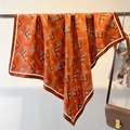 Detail of a bright orange silk scarf with letter print and twill texture on a rack - 90*90cm / Orange