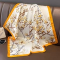 Detail eines Seidenschals mit Magnolienmuster auf Lederhintergrund mit Accessoires - Gelber Rand (W-195-2)