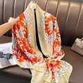 Elegante chal de seda floral naranja y champán drapeado sobre sofá de cuero - Naranja